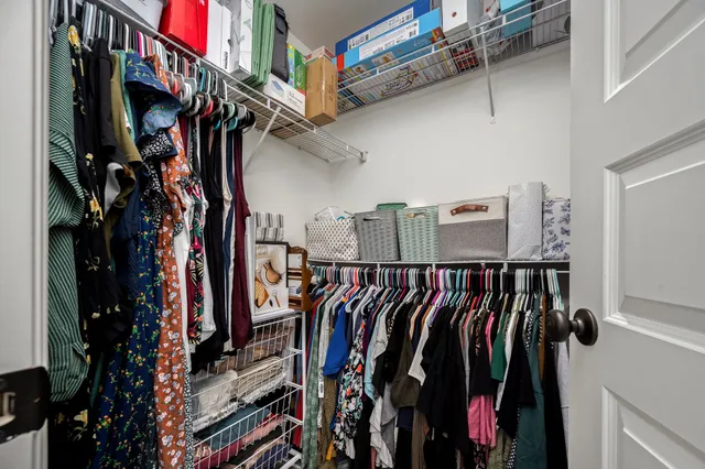 a view of walk in closet with clothes and shoes