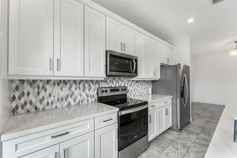 a kitchen with stainless steel appliances granite countertop white cabinets sink and stove
