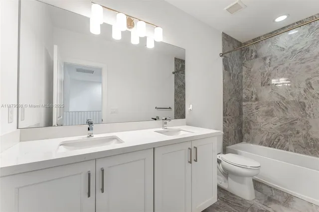 a bathroom with a double vanity sink toilet mirror and shower