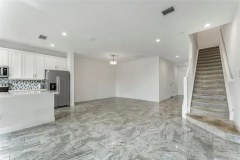 a view of kitchen with refrigerator and white cabinets