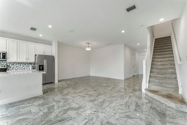 a view of kitchen with refrigerator and white cabinets