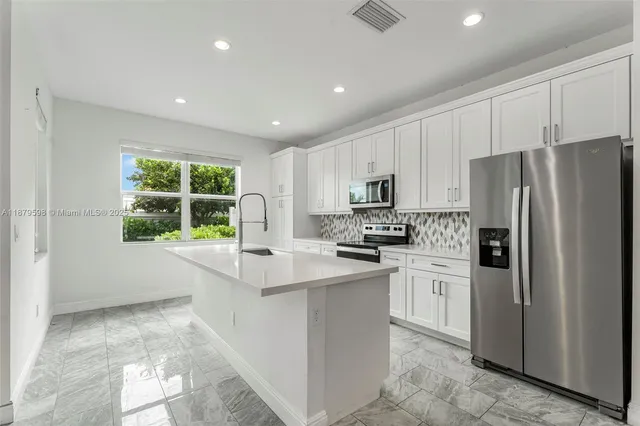 a kitchen with stainless steel appliances a refrigerator sink and microwave