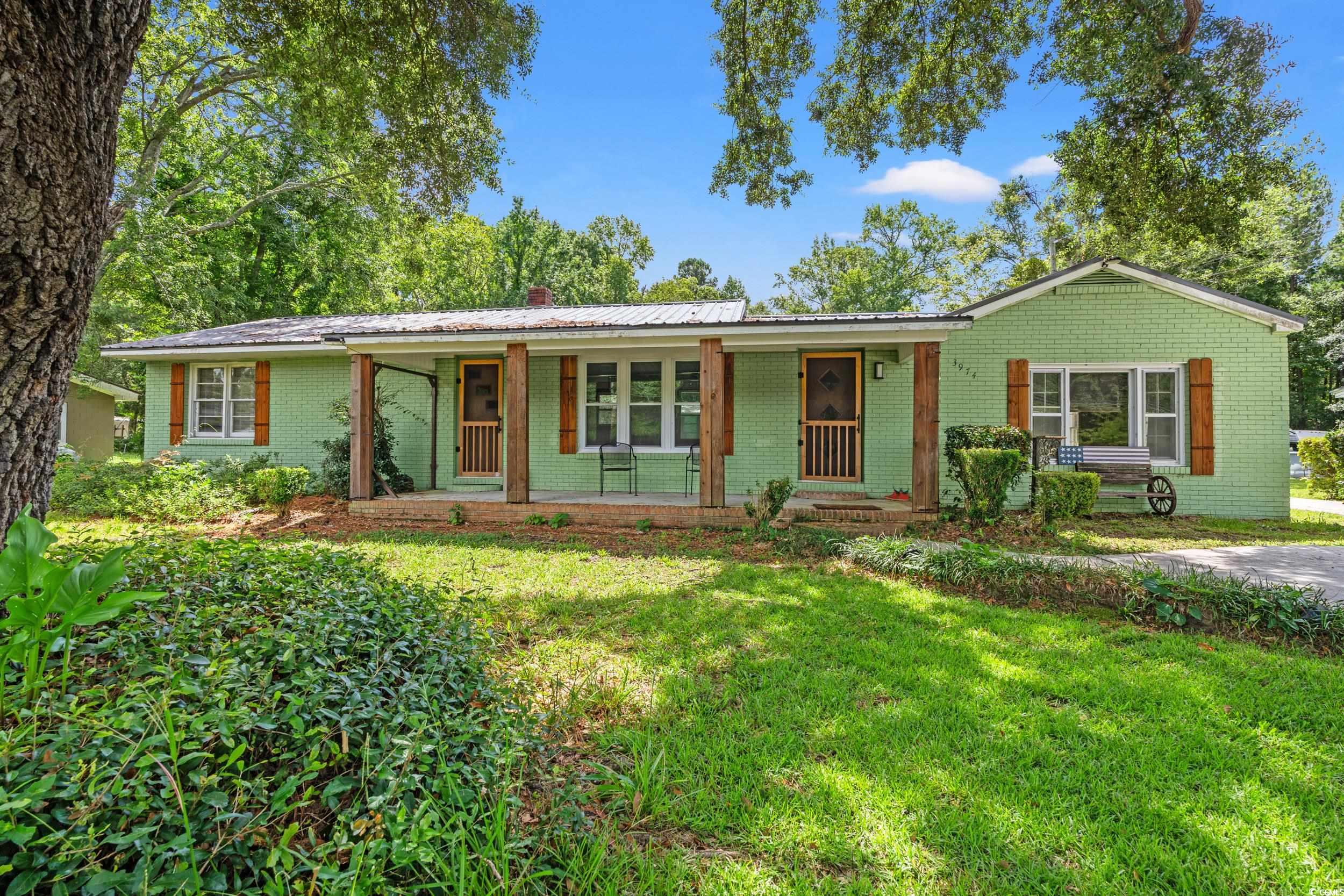3974 North Fraser Street Georgetown, SC 29440 - Photo 1 of 36 Ranch-style home with a metal roof, a front lawn, brick siding, and covered porch