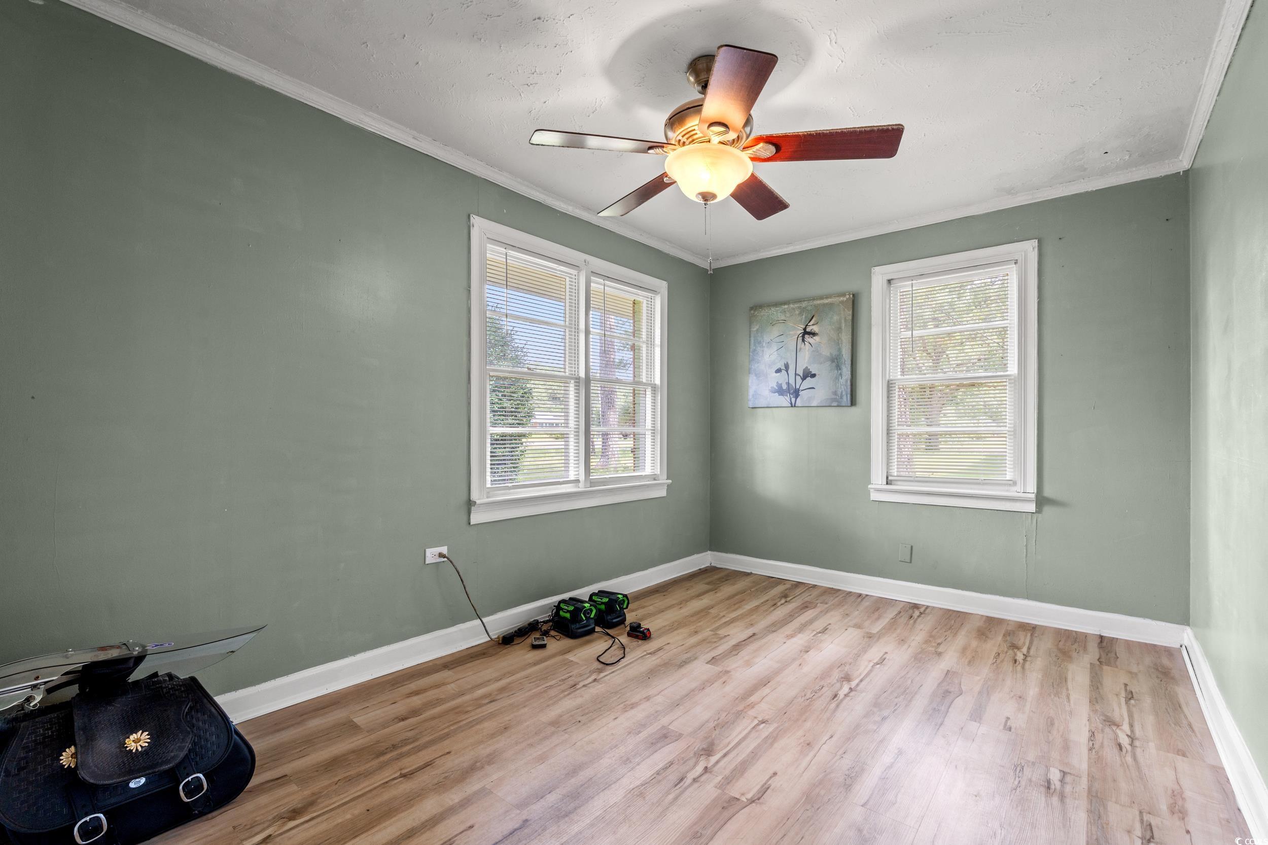 3974 North Fraser Street Georgetown, SC 29440 - Photo 11 of 36 Unfurnished room featuring light wood-style floors, crown molding, and a ceiling fan