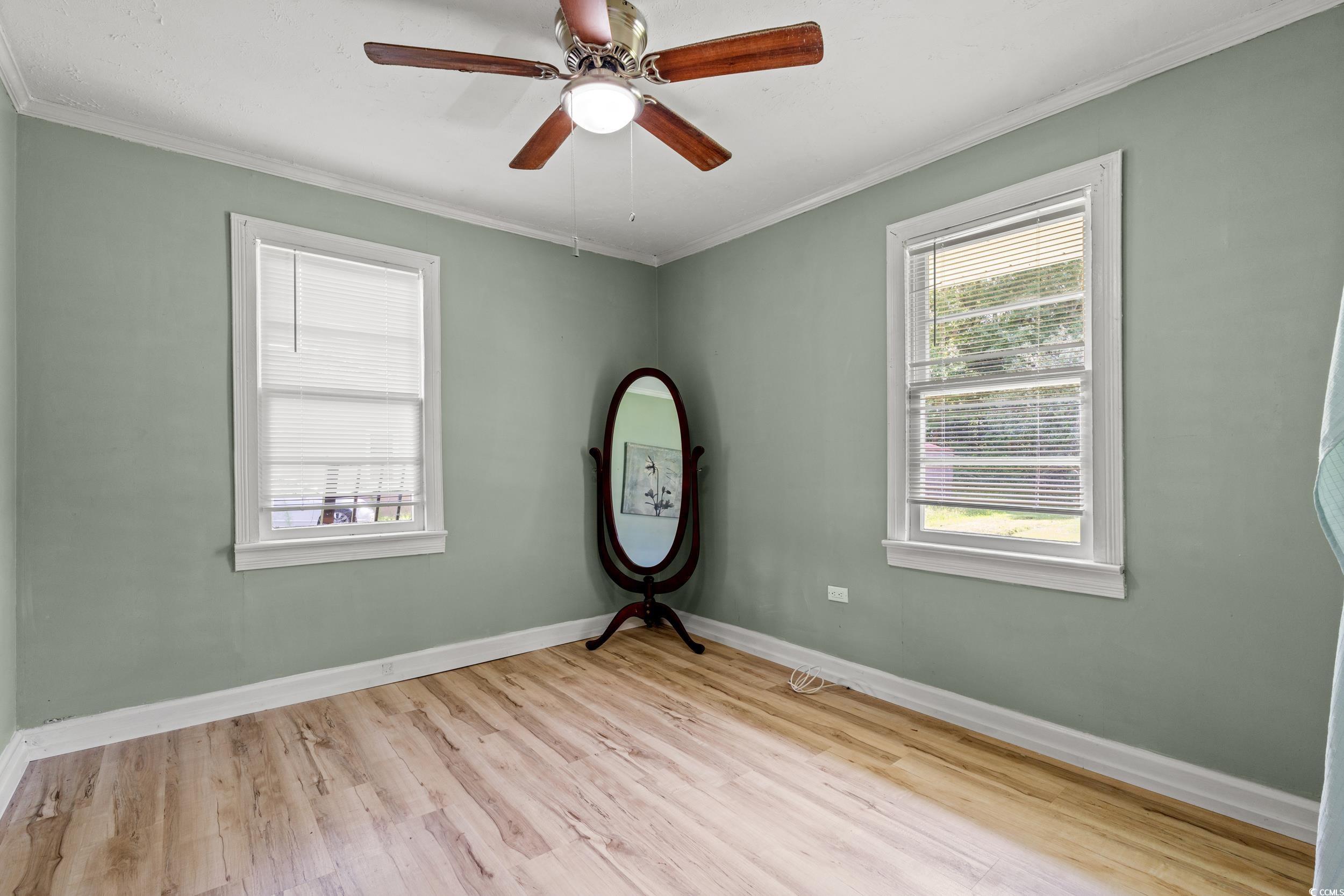 3974 North Fraser Street Georgetown, SC 29440 - Photo 13 of 36 Spare room featuring healthy amount of natural light, wood finished floors, ornamental molding, and ceiling fan