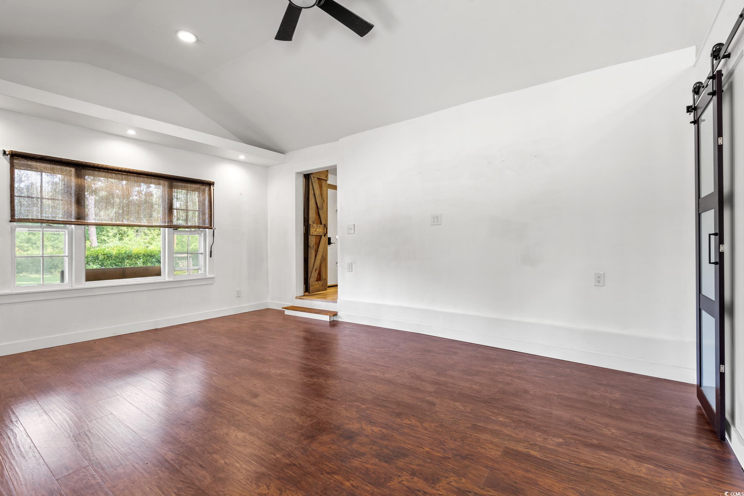 3974 North Fraser Street Georgetown, SC 29440 - Photo 18 of 36 Spare room featuring a barn door, vaulted ceiling, ceiling fan, dark wood-style floors, and recessed lighting