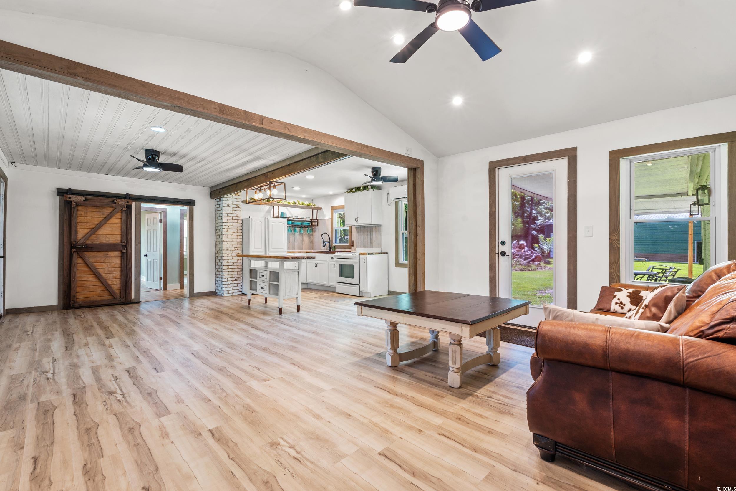 3974 North Fraser Street Georgetown, SC 29440 - Photo 2 of 36 Living area with a barn door, a ceiling fan, lofted ceiling, light wood finished floors, and recessed lighting