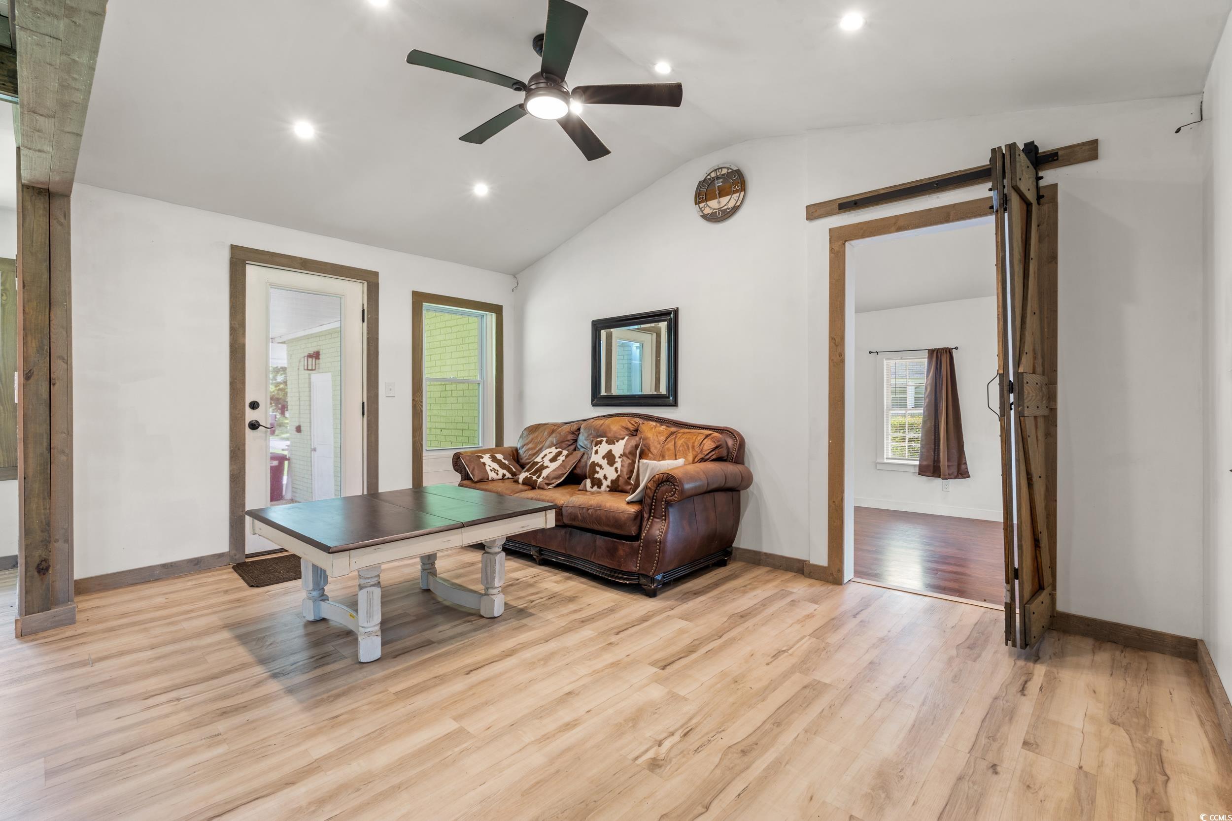 3974 North Fraser Street Georgetown, SC 29440 - Photo 7 of 36 Living area featuring vaulted ceiling, a barn door, light wood-style floors, plenty of natural light, and ceiling fan