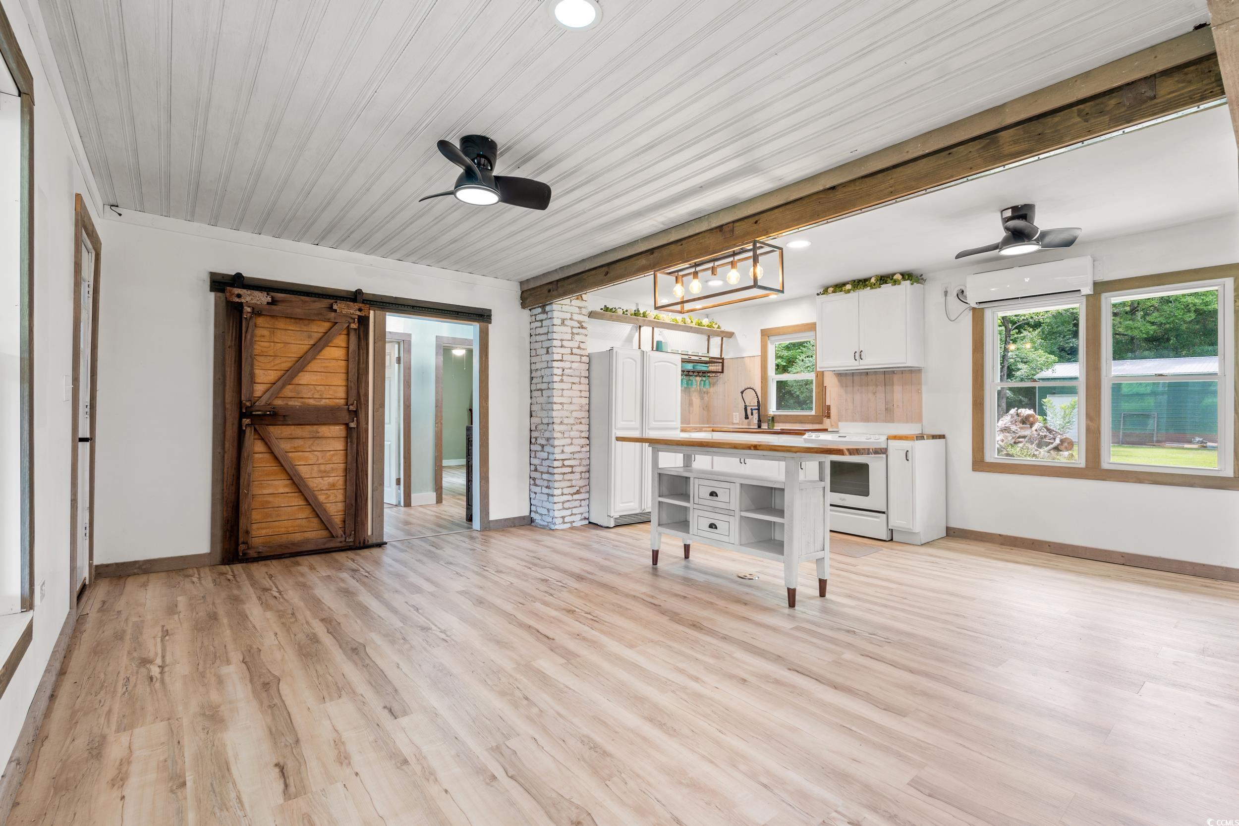 3974 North Fraser Street Georgetown, SC 29440 - Photo 10 of 36 Kitchen with light countertops, ceiling fan, a barn door, white cabinets, and a breakfast bar