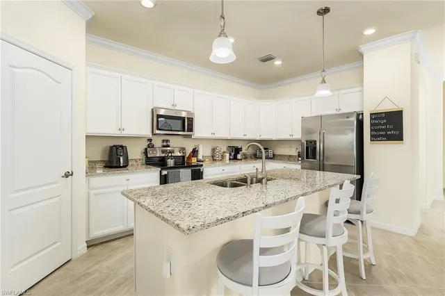 a kitchen with granite countertop stainless steel appliances a refrigerator a stove a sink and white cabinets