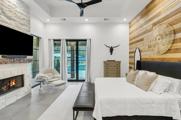 a bedroom with a bed a flat screen tv and a fireplace