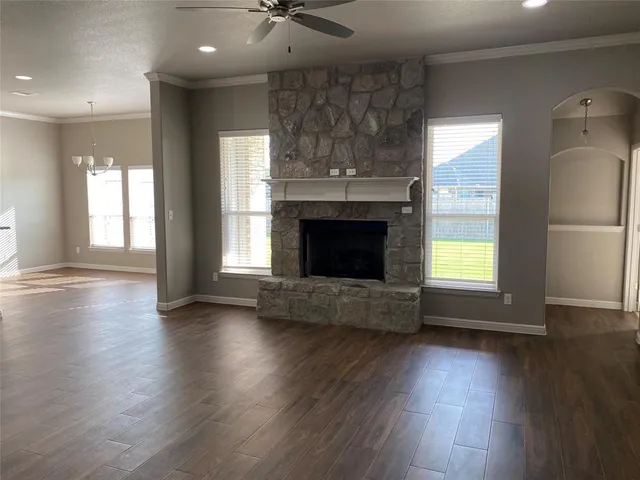 an empty room with wooden floor a fireplace and windows