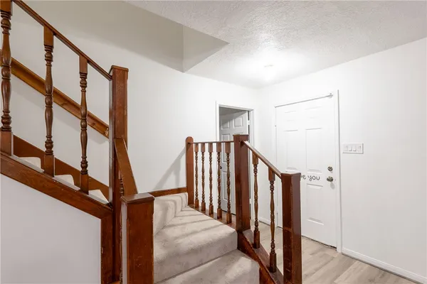 a view of staircase with lots of frames on wall and a window