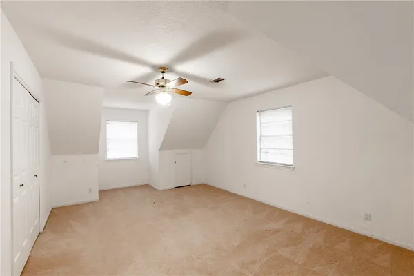 an empty room with windows and chandelier fan