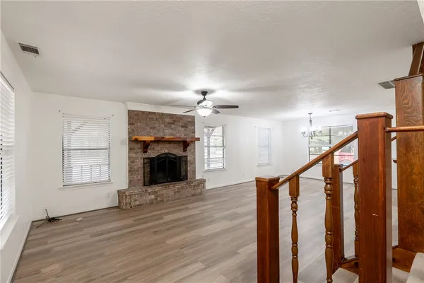 a view of an empty room with wooden floor fireplace and a window