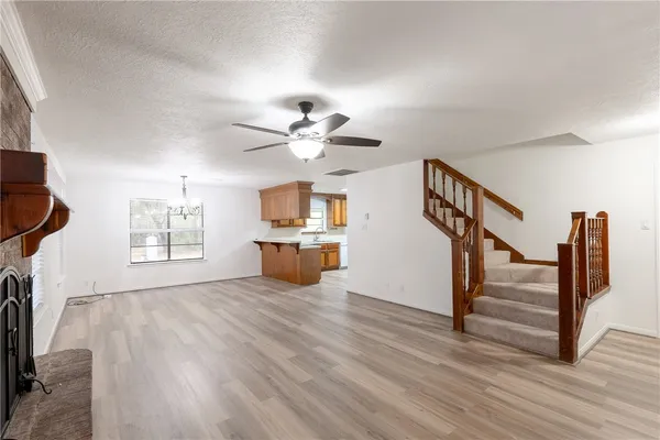 a view of an empty room with wooden floor and a ceiling fan