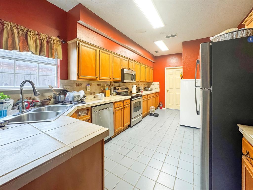 5510 Rolling Green Road Arlington, TX 76017 - Photo 8 of 19 a kitchen with a sink a refrigerator and cabinets