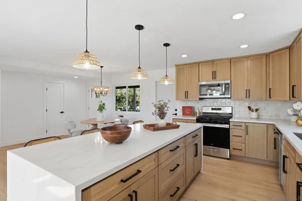 a kitchen with stainless steel appliances kitchen island granite countertop a sink a stove and a wooden floors