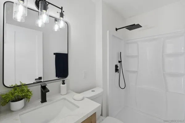 a bathroom with a sink a light fixture and a shower