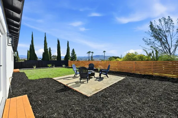 a view of a chairs and table in patio and yard