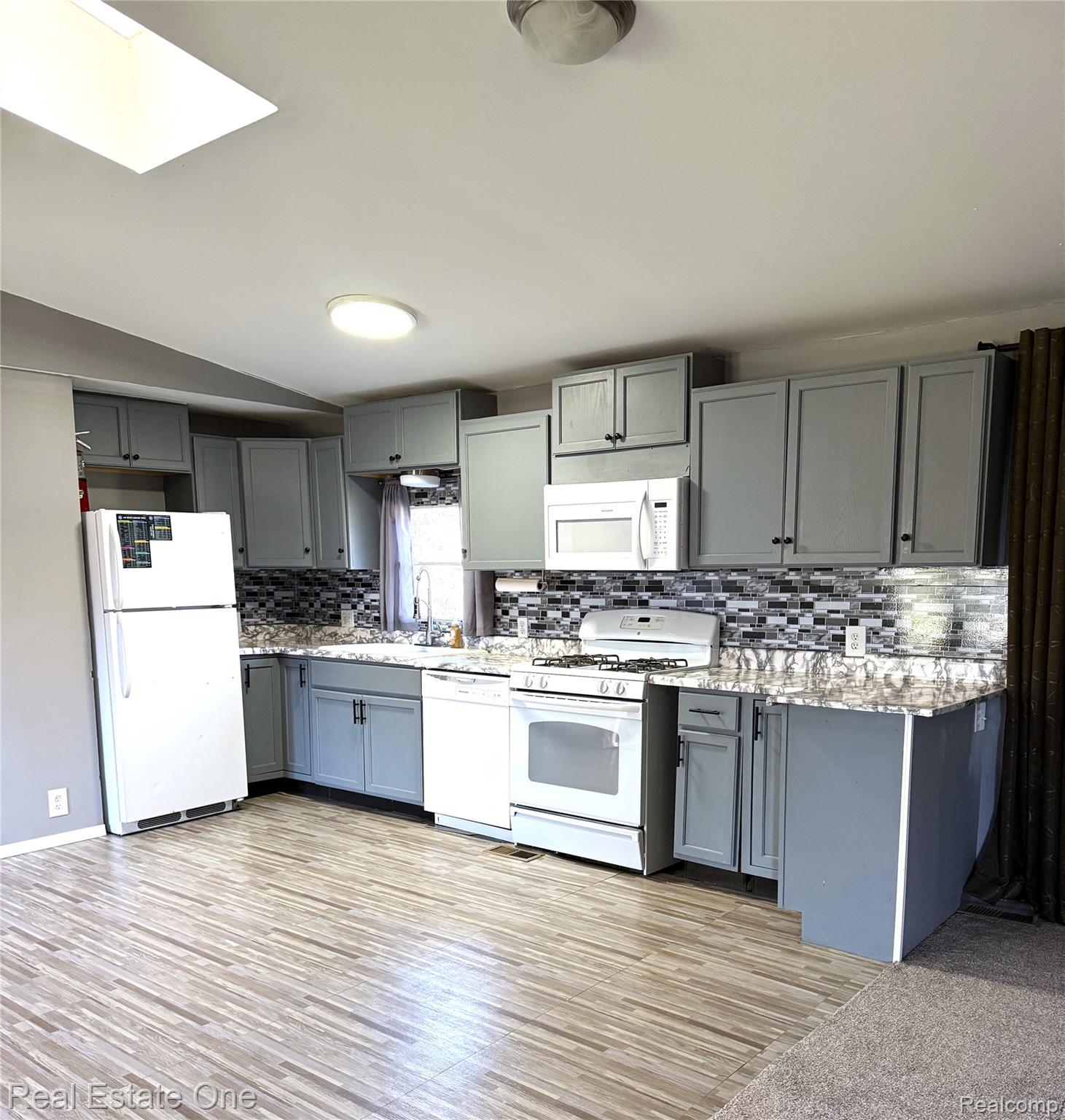 786 Chestnut Street Fowlerville, MI 48836 - Photo 4 of 19 Recessed lighting, wood-finish flooring, gray cabinetry with dark hardware, a tile backsplash, and white appliances