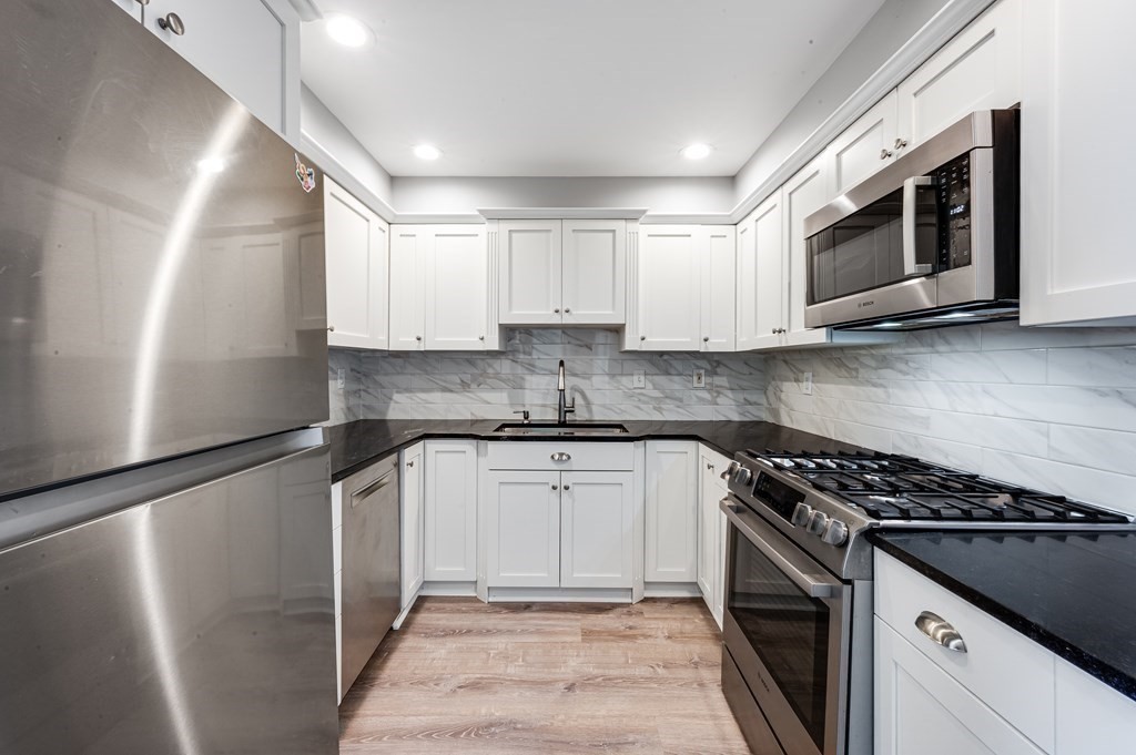 a kitchen with stainless steel appliances granite countertop a stove a microwave and a refrigerator