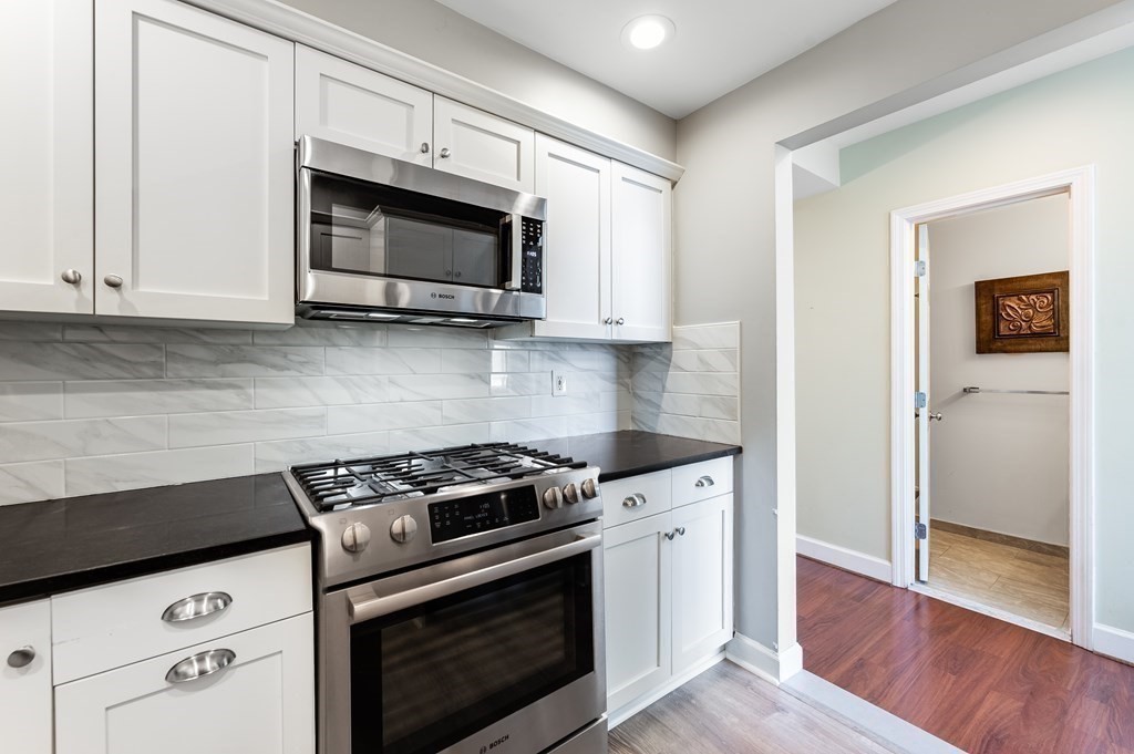 116 Milton Street, Unit 231 Dedham, MA 02026 - Photo 2 of 27 a kitchen with stainless steel appliances white cabinets and a stove a oven with wooden floor
