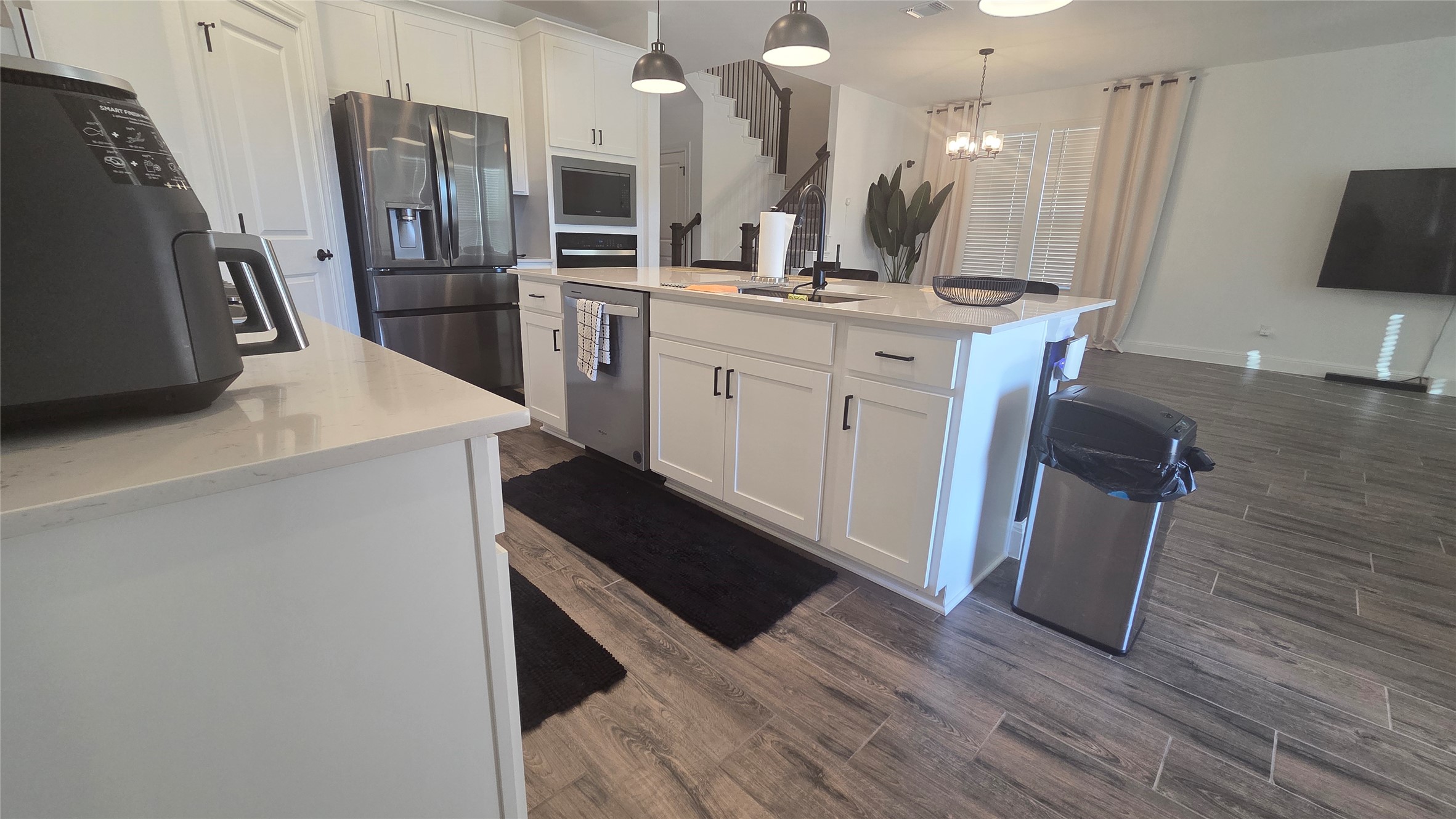 125 Raleigh Drive Georgetown, TX 78633 - Photo 5 of 30 Kitchen with dark wood finished floors, light stone countertops, white cabinetry, stainless steel appliances, and a kitchen island with sink