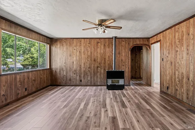 a view of a livingroom with wooden floor a ceiling fan and windows