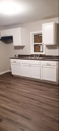 a view of kitchen with stainless steel appliances a sink and wooden floor