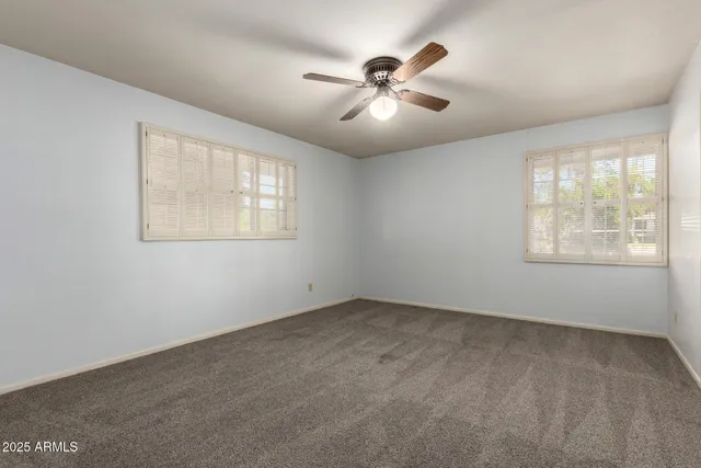 an empty room with windows and fan
