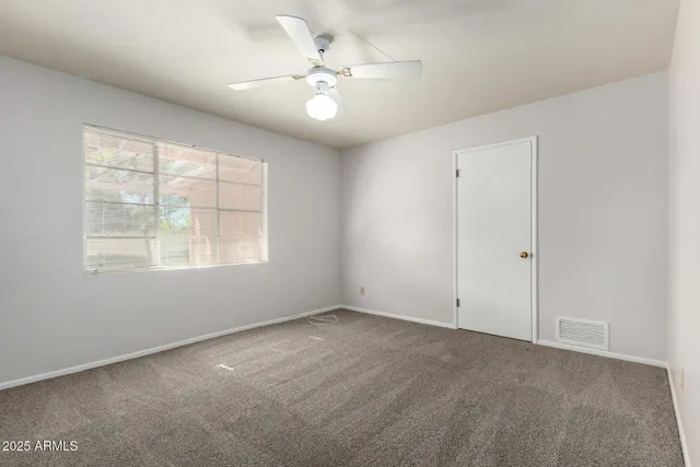 an empty room with windows and chandelier fan