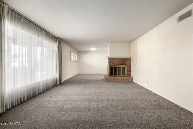 a view of an empty room with a fireplace and a window