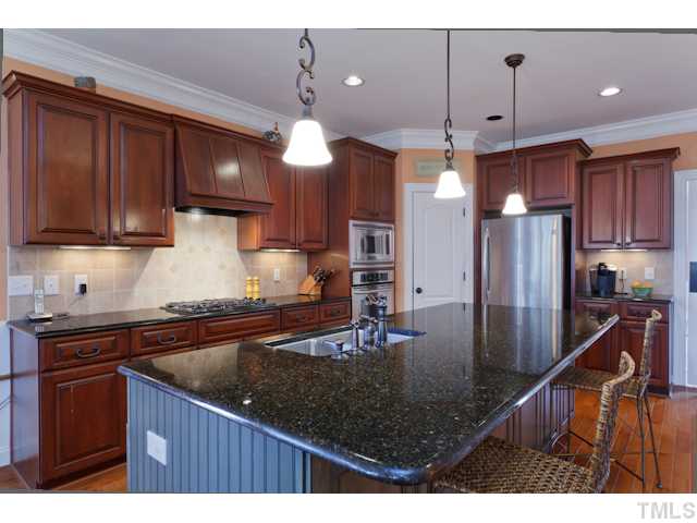 4216 Oakthorne Way Raleigh, NC 27613 - Photo 9 of 24 a kitchen with stainless steel appliances granite countertop a sink a refrigerator and wooden cabinets
