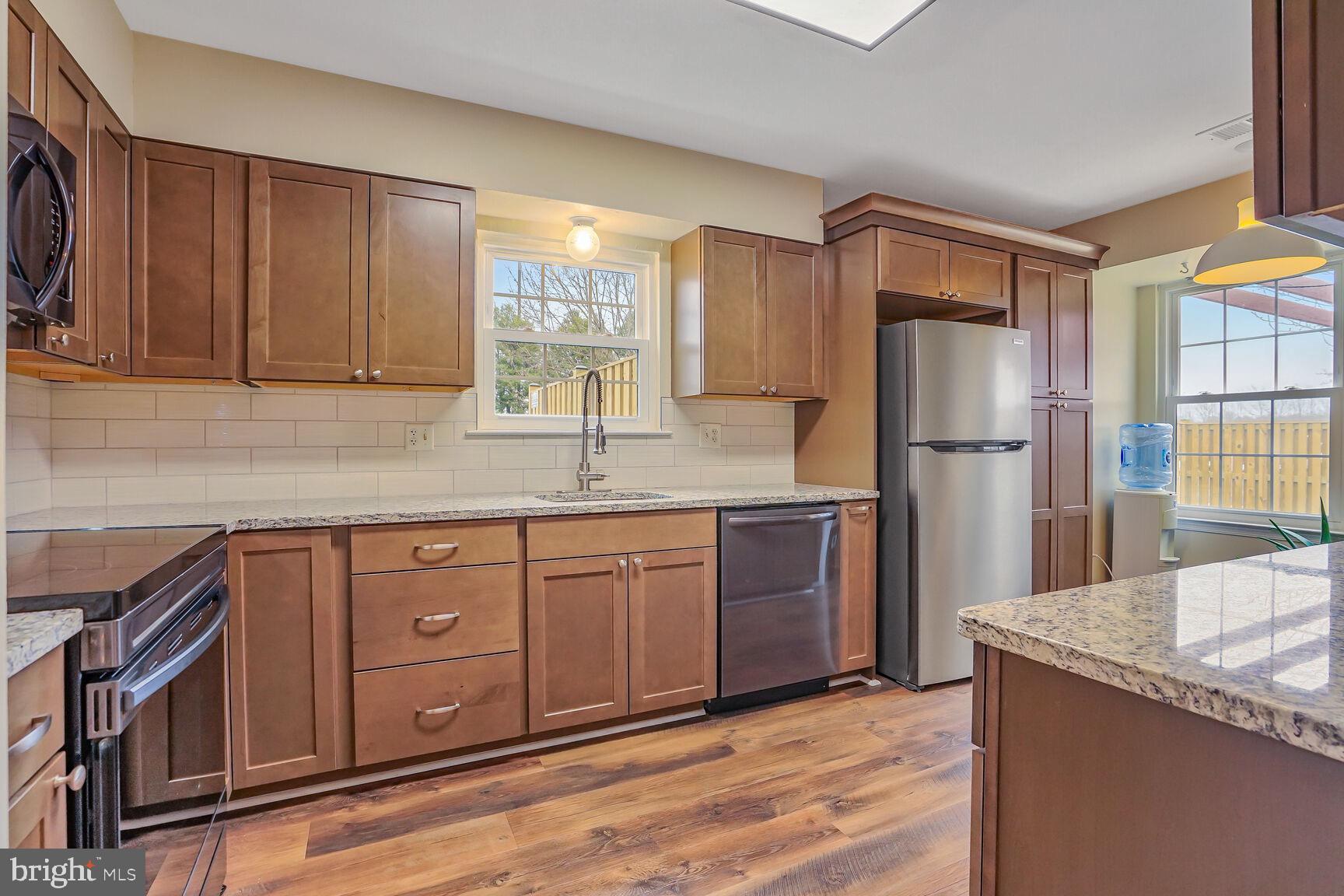 7810 Gateshead Lane Manassas, VA 20109 - Photo 2 of 20 a kitchen with stainless steel appliances granite countertop a refrigerator a sink dishwasher a oven with wooden cabinets and floor