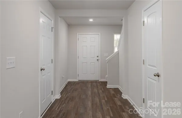 a view of a hallway with wooden floor and a bathroom