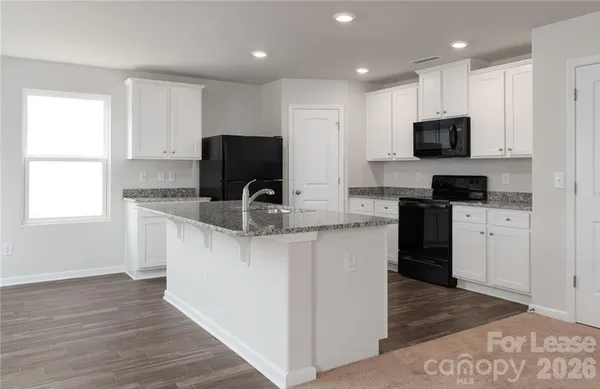 a kitchen with granite countertop a refrigerator and a stove top oven