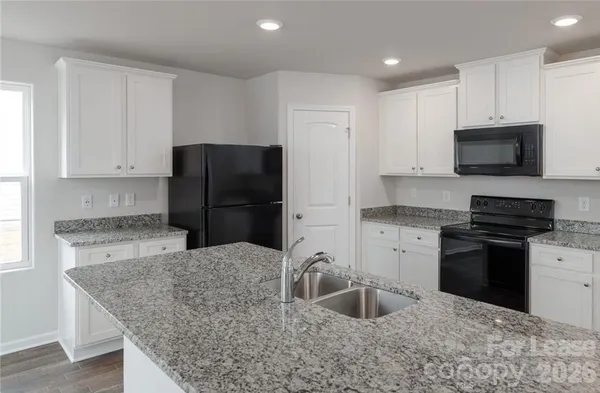 a kitchen with granite countertop a refrigerator and a stove top oven