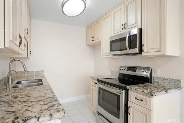 a kitchen with granite countertop white cabinets stainless steel appliances and sink