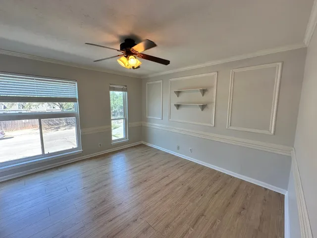 a view of an empty room with a window and wooden floor