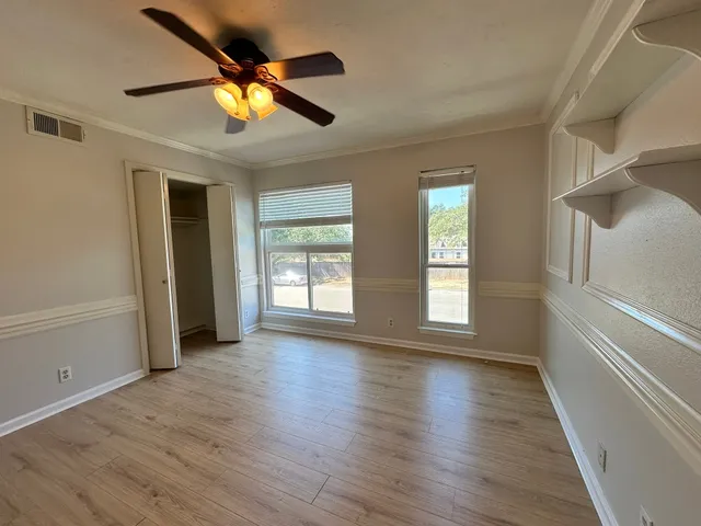 an empty room with wooden floor and windows