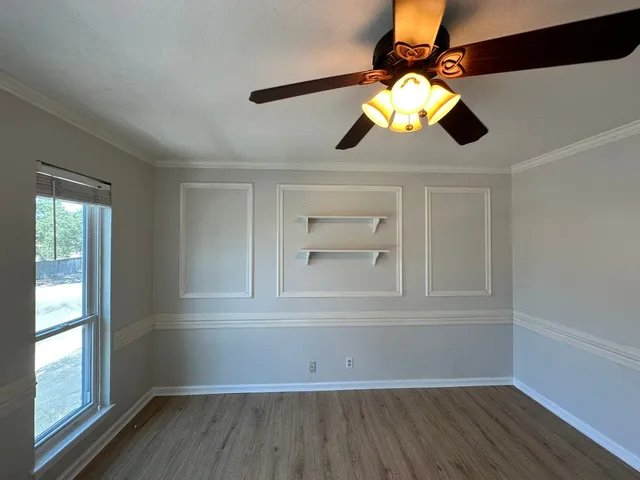 an empty room with wooden floor cabinet and windows