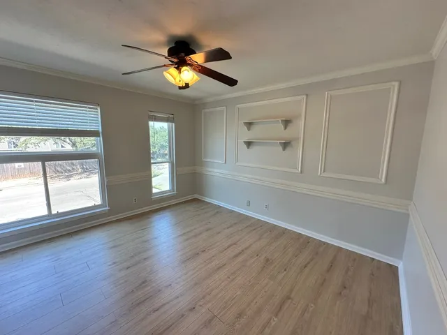 a view of an empty room with a window and wooden floor