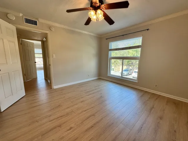 a view of an empty room with wooden floor and a window