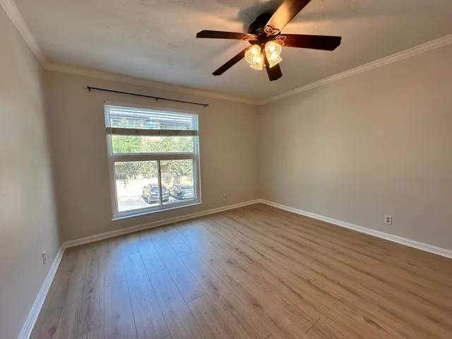 an empty room with wooden floor ceiling fan and windows
