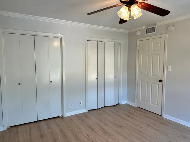 an empty room with wooden floor fan and windows