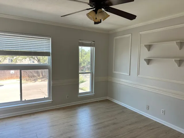 a view of an empty room with a window and wooden floor