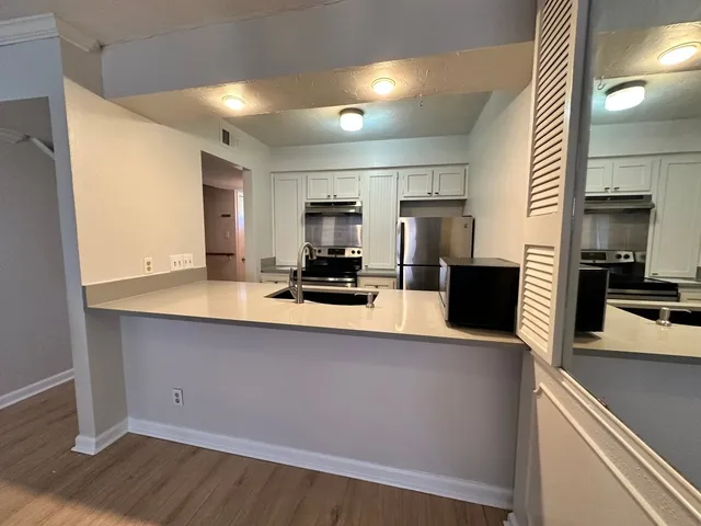 a kitchen with a sink a counter top space cabinets and stainless steel appliances