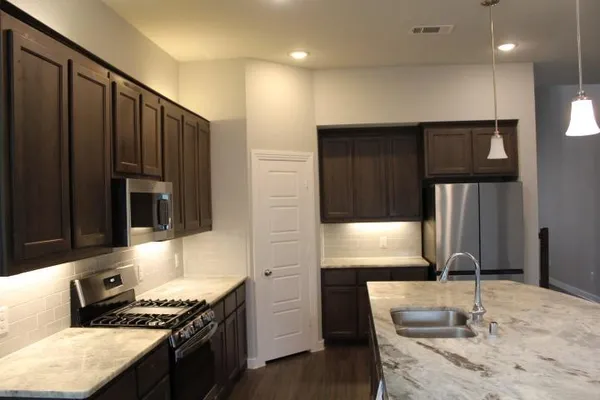 a kitchen with kitchen island granite countertop a stove and a refrigerator