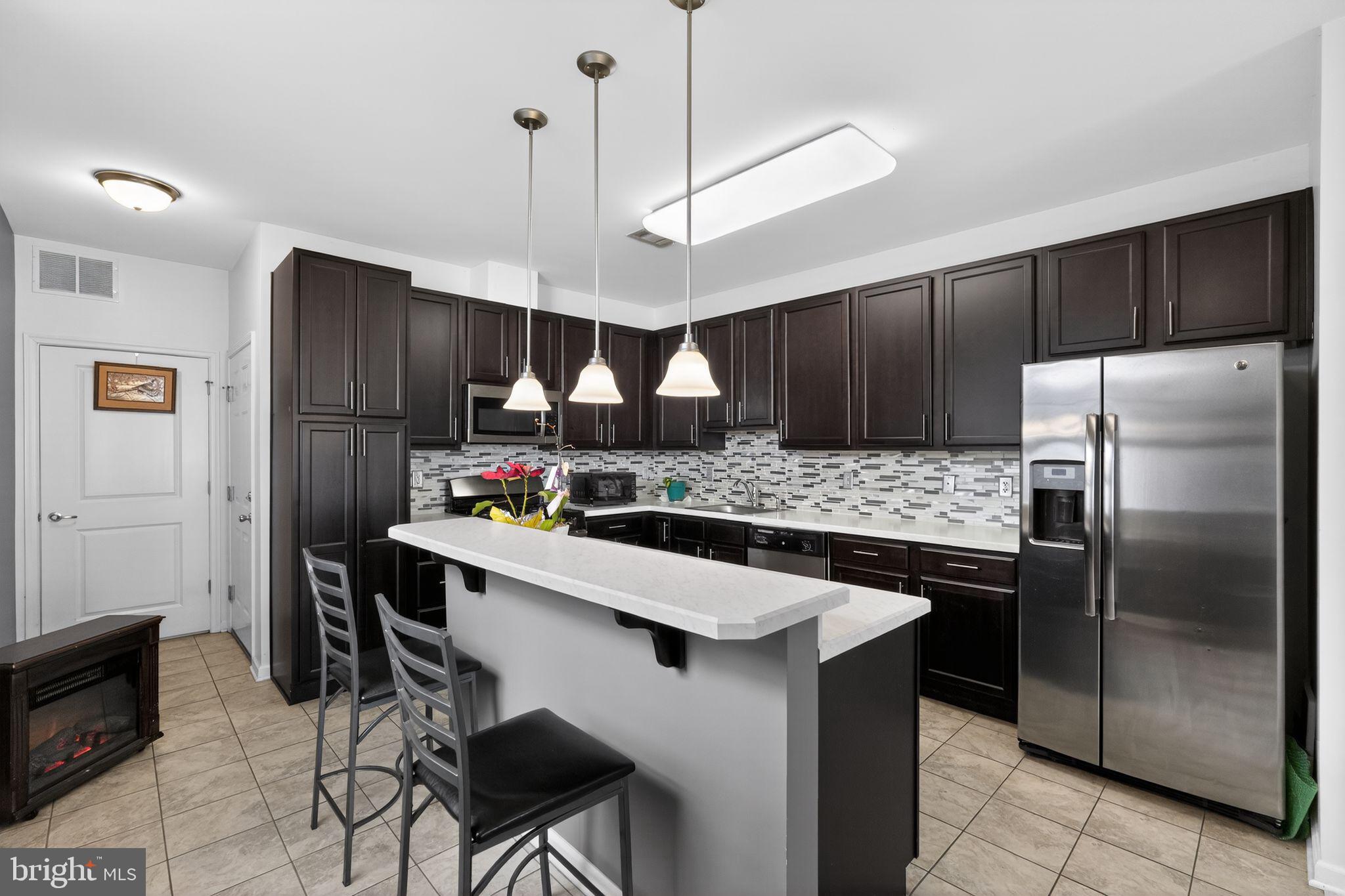 33 Rowand Way East Clementon, NJ 08021 - Photo 5 of 15 a kitchen with stainless steel appliances kitchen island granite countertop a refrigerator a stove a sink a dining table and chairs with wooden floor